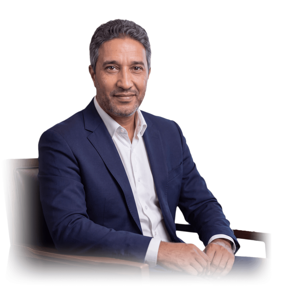 Portrait of Aziz Mimoudi in a navy suit, seated in a wooden armchair