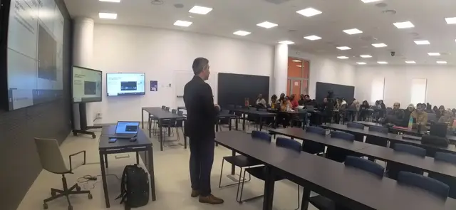Wide view of a UM6P training room: Aziz Mimoudi presenting, participants at long tables