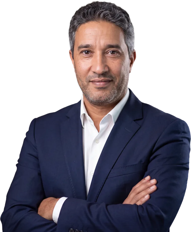 Portrait of Aziz Mimoudi in a navy suit, arms crossed